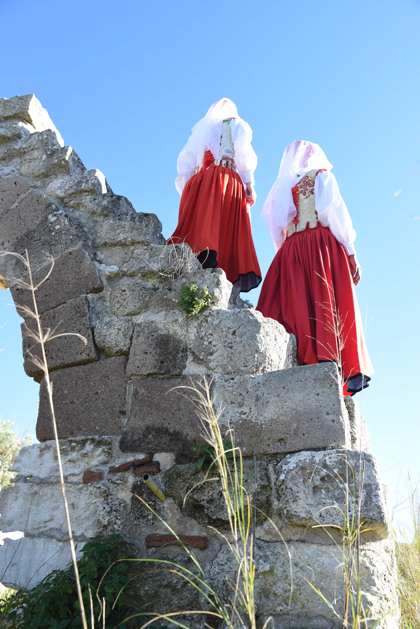 Due donne in costume tradizionale sardo su una roccia, controcielo